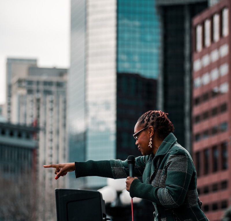 woman in green jacket standing near building during daytime